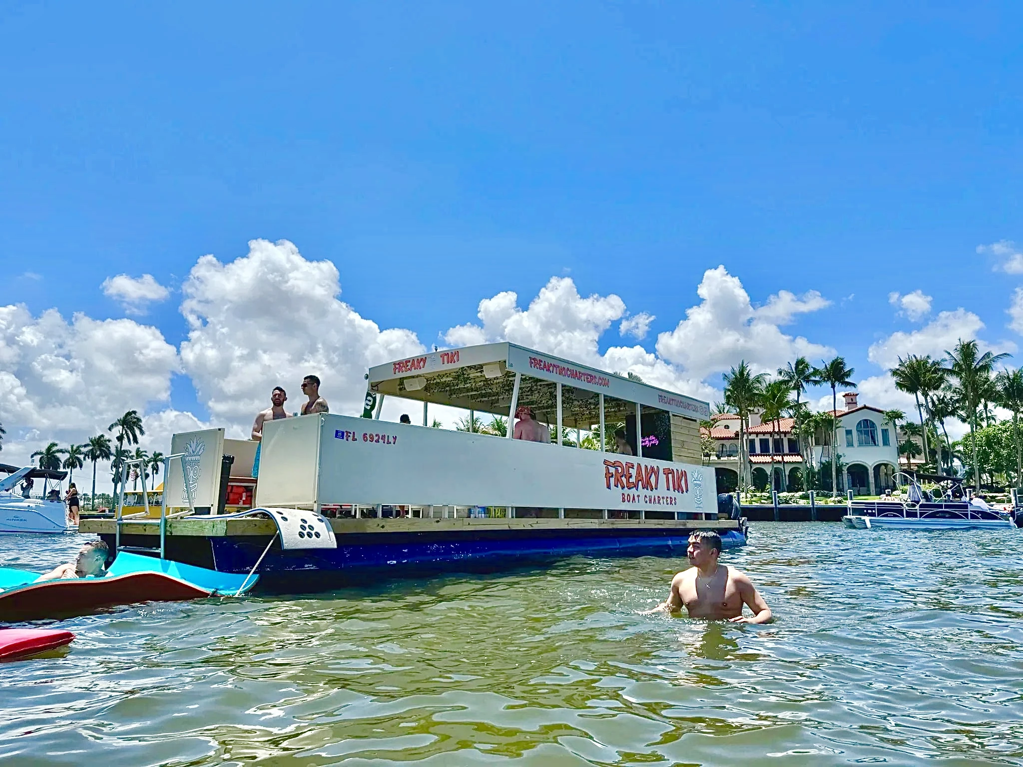 Freaky Tiki private party boat beside swimmers and a floating mat at the Fort Lauderdale sandbar