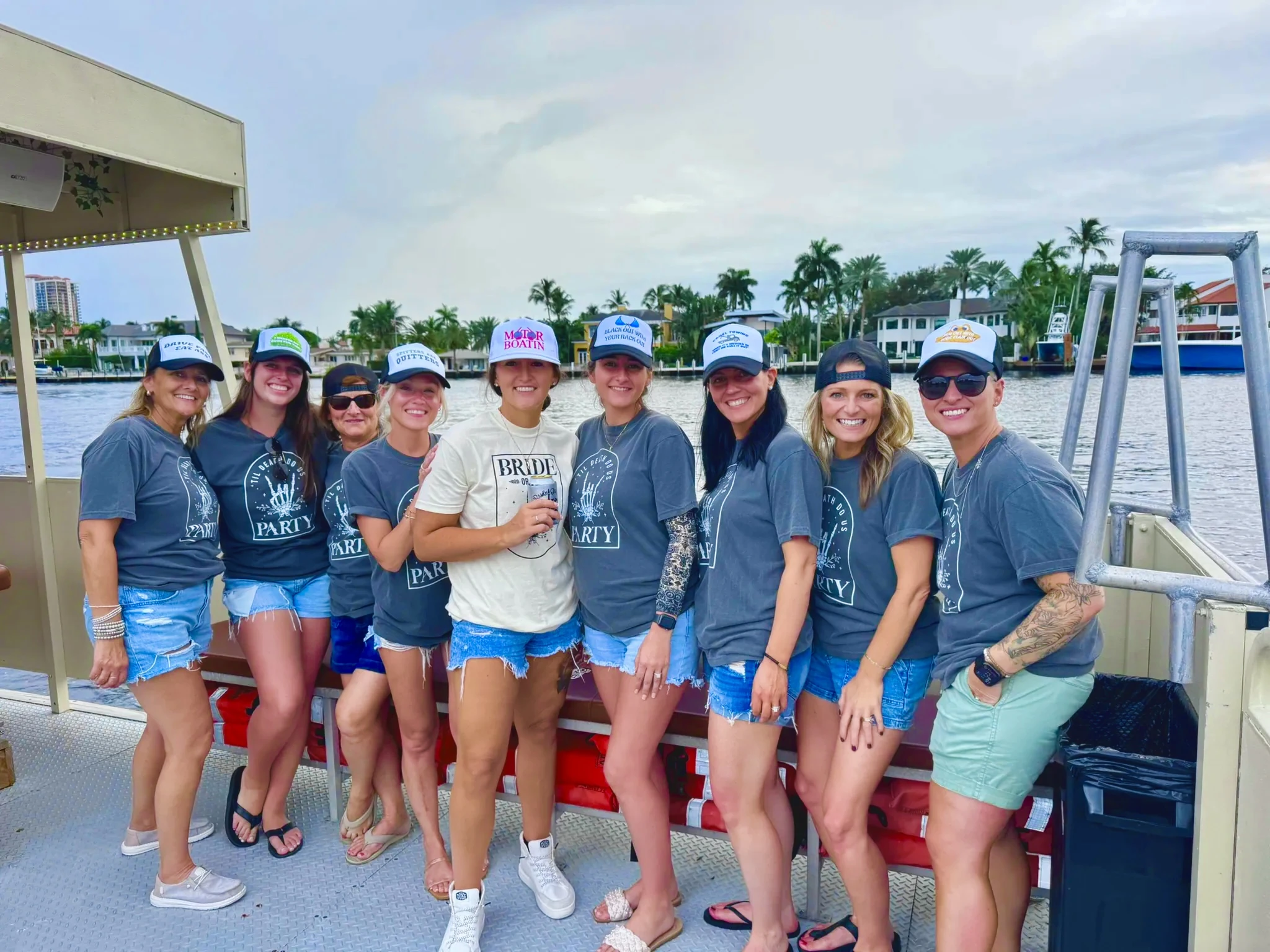 Wedding-party group with the bride in a white shirt and her bachelorette crew in matching blue shirts aboard Freaky Tiki