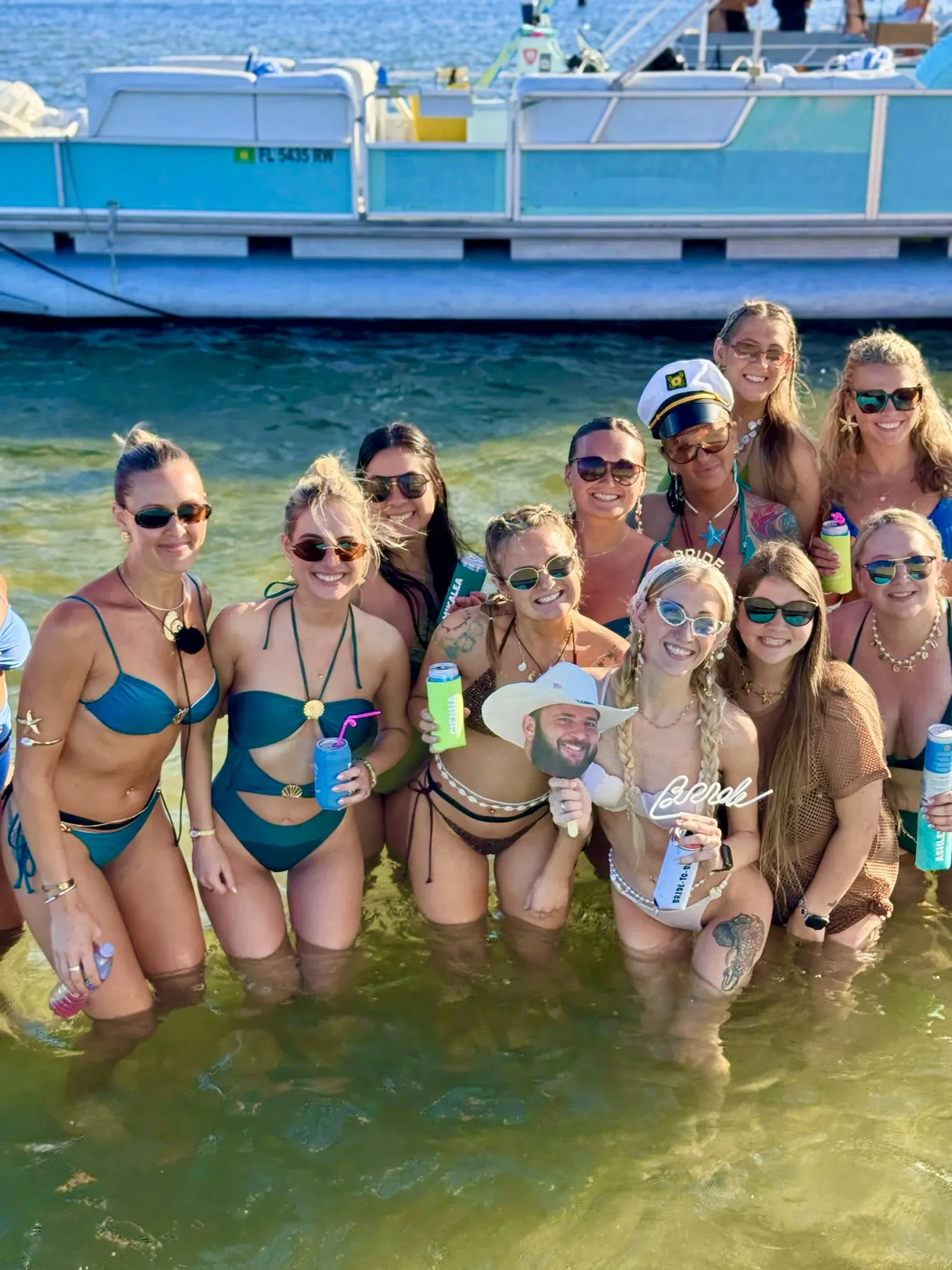 Bachelorette party group posing together in the Fort Lauderdale sandbar water with the bride and a groom-face prop
