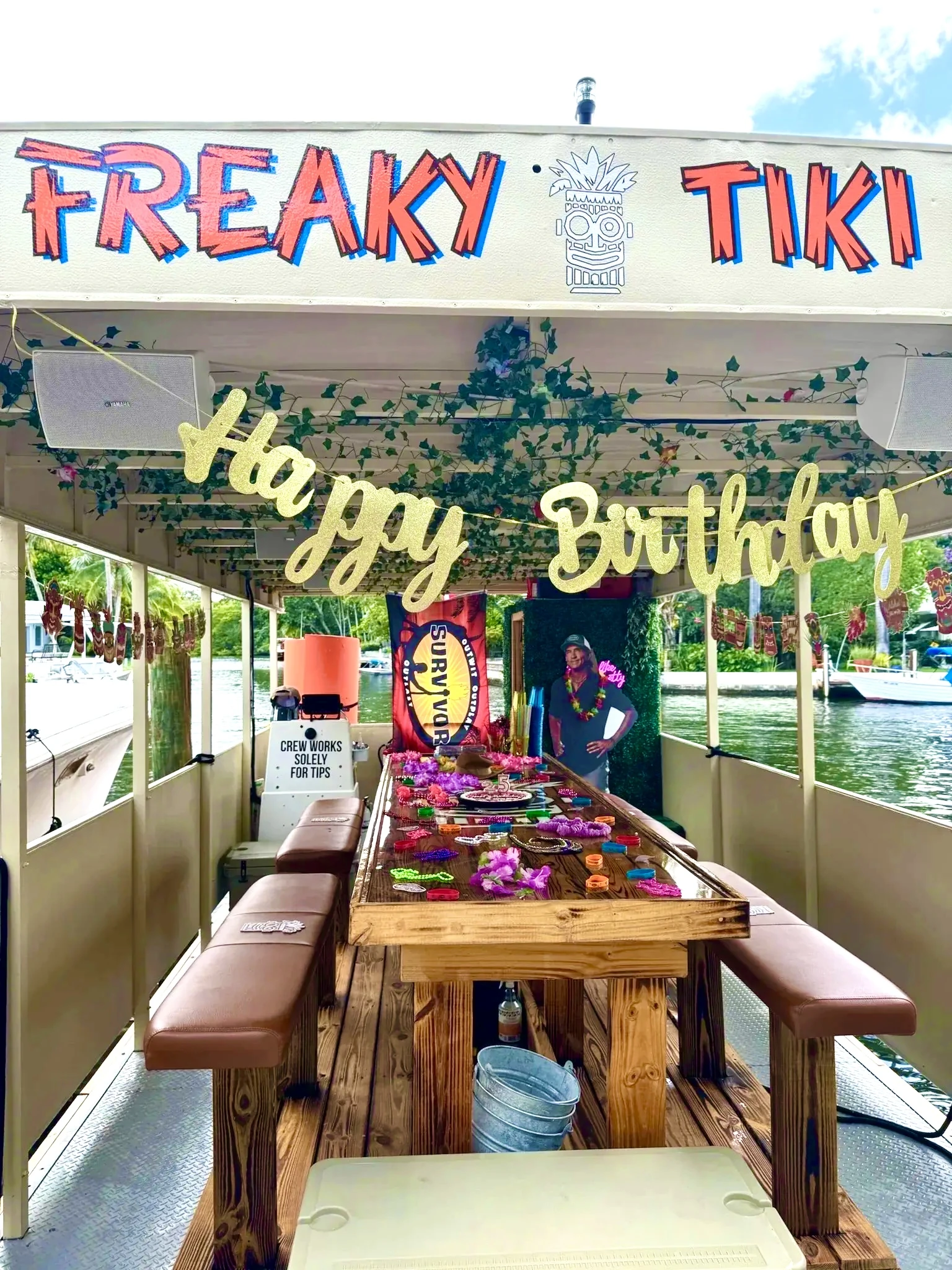 Happy Birthday banner, colorful leis and party decorations around the Freaky Tiki table in Fort Lauderdale